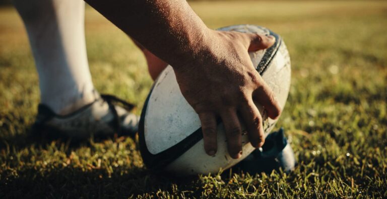 Rugby player with hands on ball.