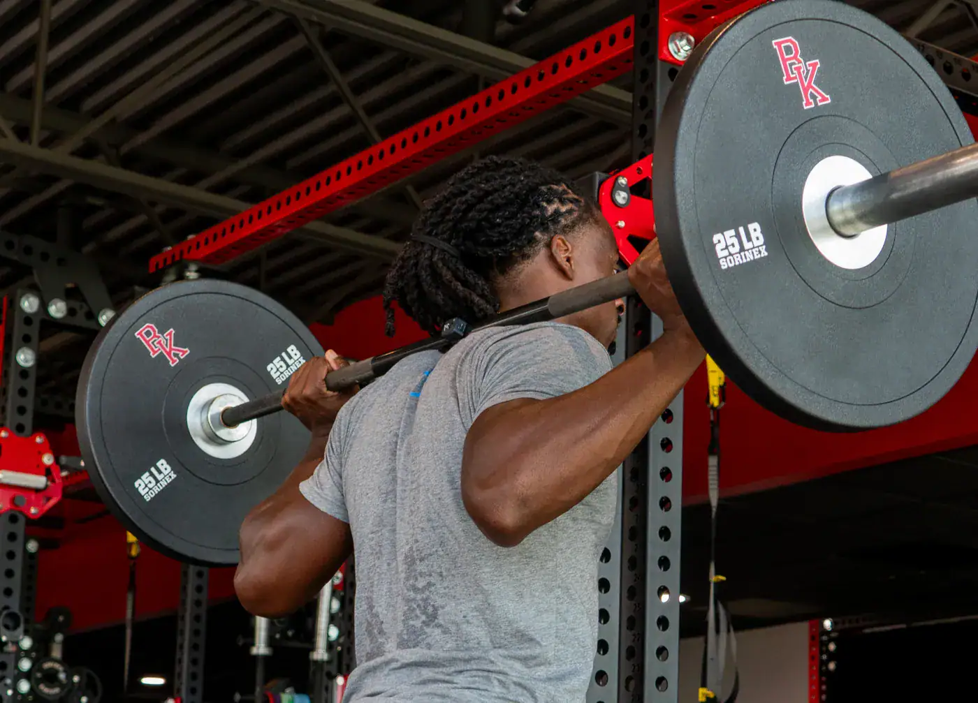 Dashr Motion sensor clipped to a loaded barbell during a back squat